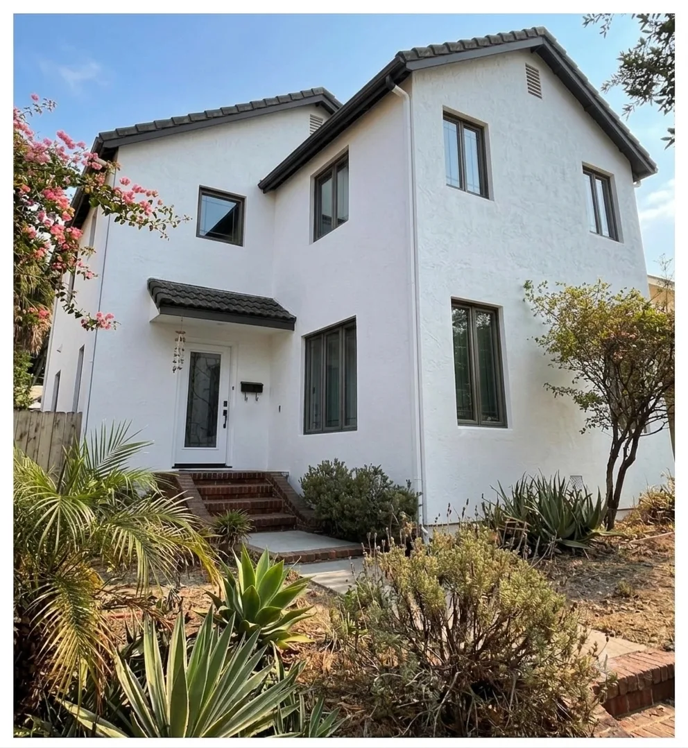 Two-story stucco home exterior after washing, restored to a clean white finish